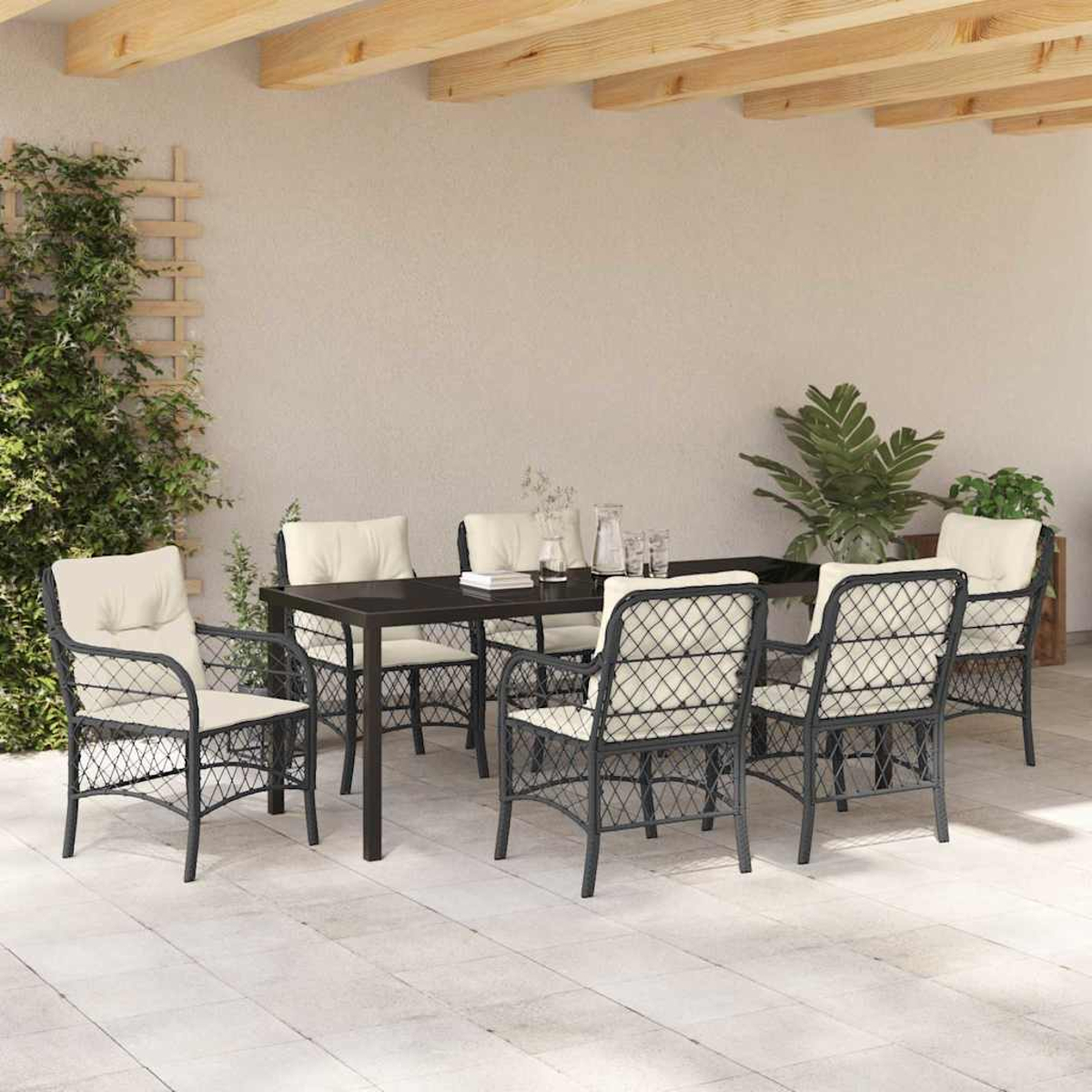 Essgruppe im Freien: schwarzer Tisch, sechs Korbstühle mit cremefarbenen Kissen, unter einer Holzbalkenstruktur, auf einer Terrasse.