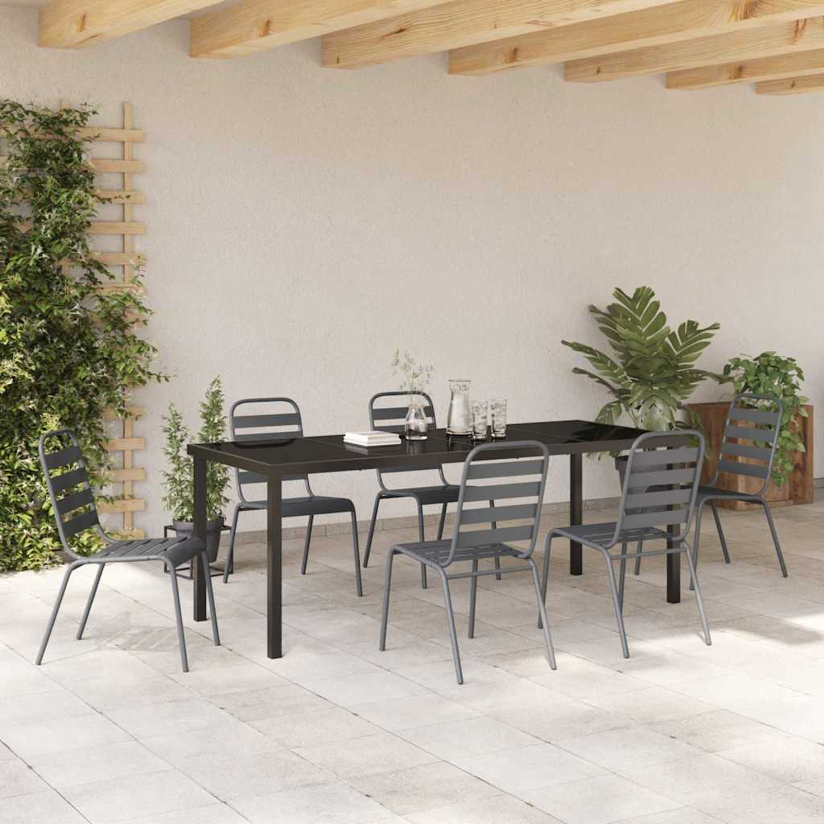 Essgruppe im Freien. Schwarzer Tisch und graue Stühle auf einer gefliesten Terrasse. Pflanzen und Holzbalken darüber.