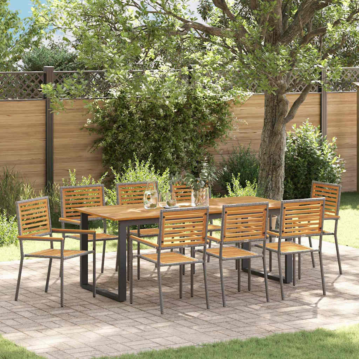 Essgruppe im Freien. Holztisch und Stühle auf einer Terrasse mit Gartenkulisse, Bäumen und Holzzaun.