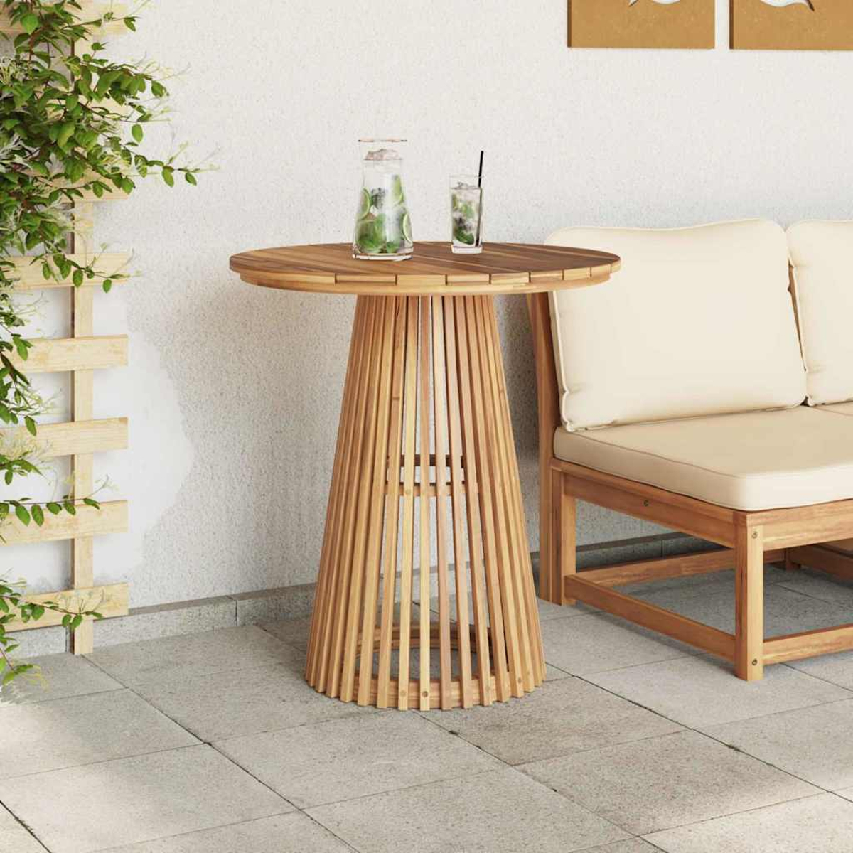 Mesa redonda de madera con bebida, base de listones de madera, junto a sofá y planta.