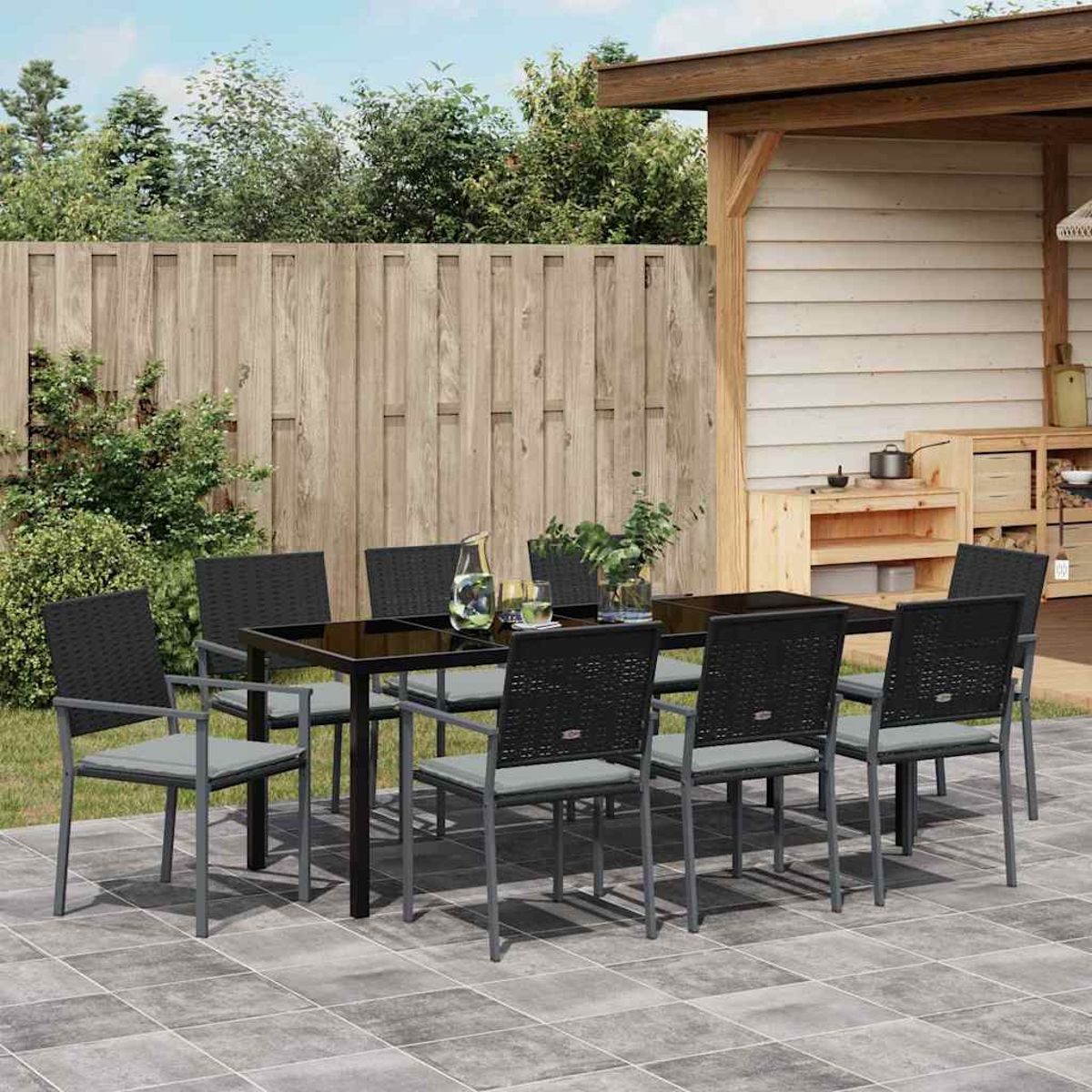Das Outdoor-Dining-Set besteht aus einem schwarzen Tisch, acht Stühlen mit grauen Kissen, auf einer gefliesten Terrasse mit Holzzaun.