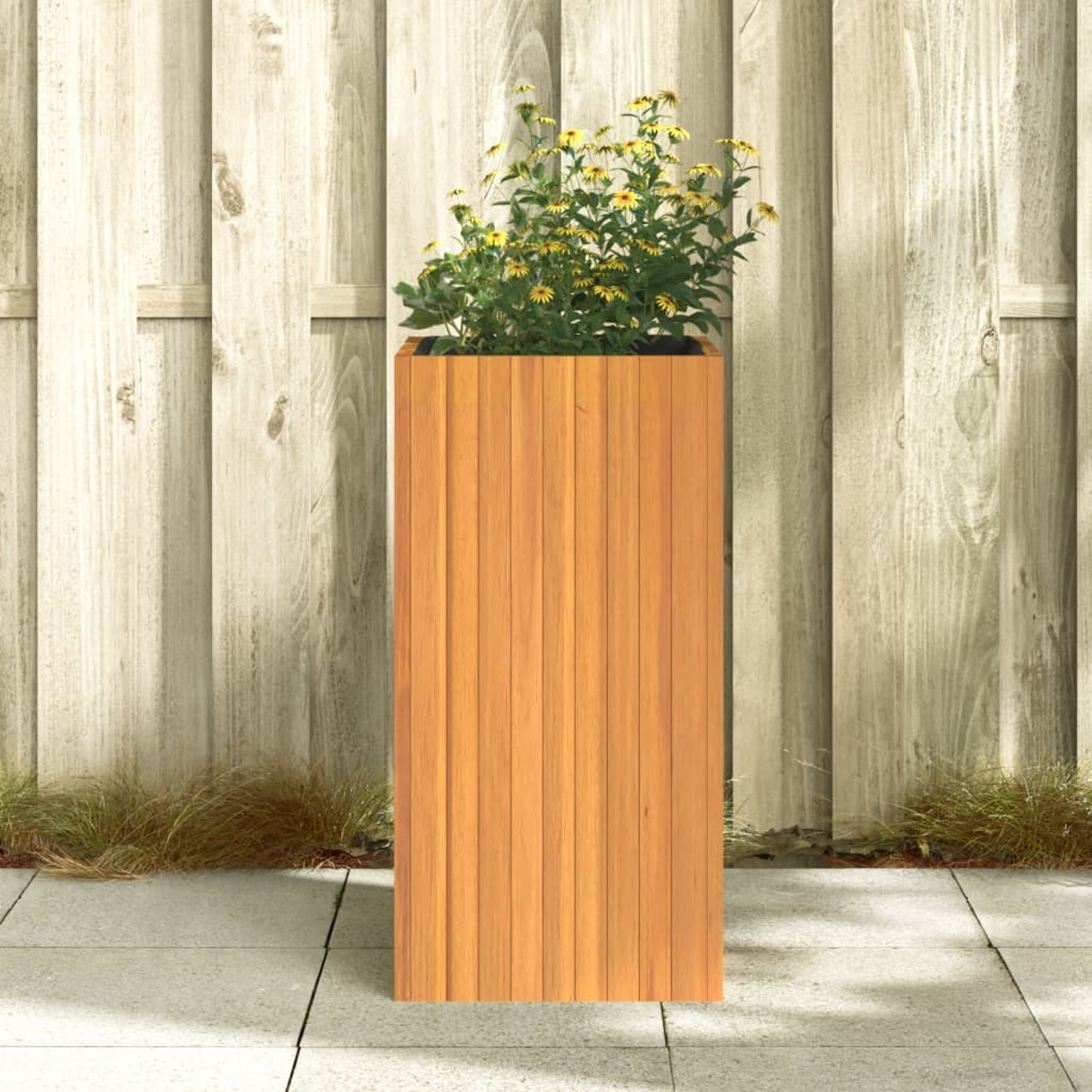 Ein hoher hölzerner Pflanzkasten mit gelben Blumen und grünen Blättern steht auf einer Terrasse. Dahinter ist ein Holzzaun.