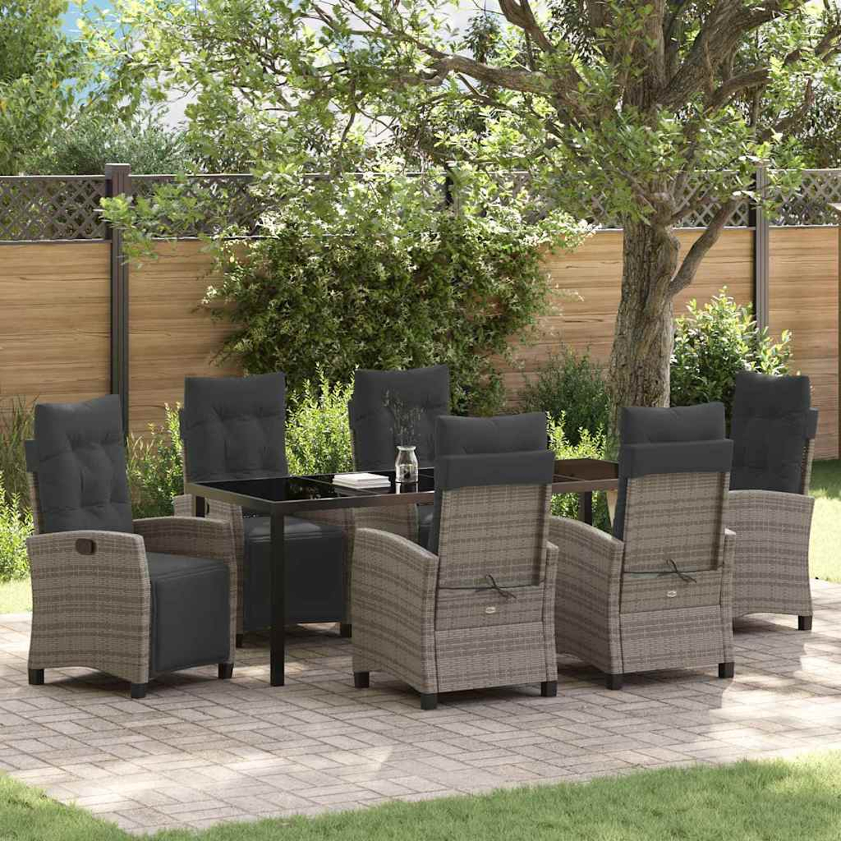 Ein Terrassenset mit Tisch und Stühlen. Die Stühle sind grau mit schwarzen Kissen. Ein Baum und ein Zaun sind im Hintergrund.