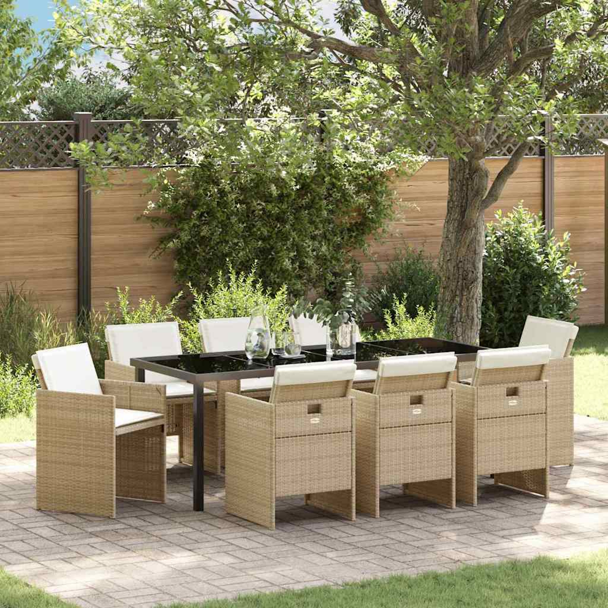 Essgruppe im Freien. Rechteckiger schwarzer Tisch mit acht Korbstühlen mit cremefarbenen Kissen. Auf einer Terrasse mit Bäumen und Holzzaun.