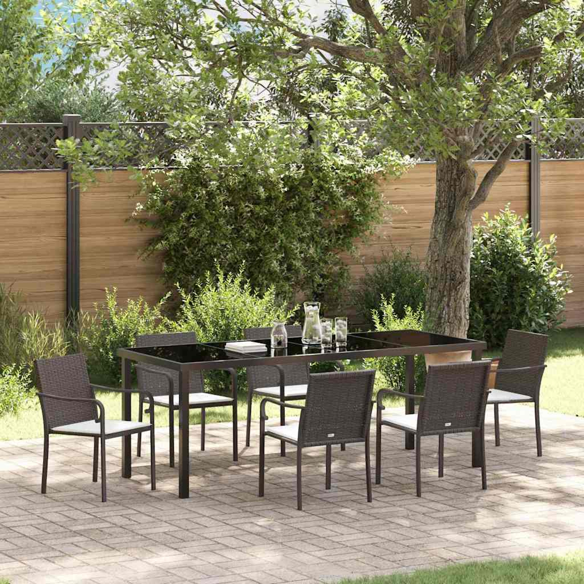 Essgruppe im Freien mit Tisch und Stühlen auf einer Terrasse. Hintergrund mit Bäumen, Büschen und Holzzaun.