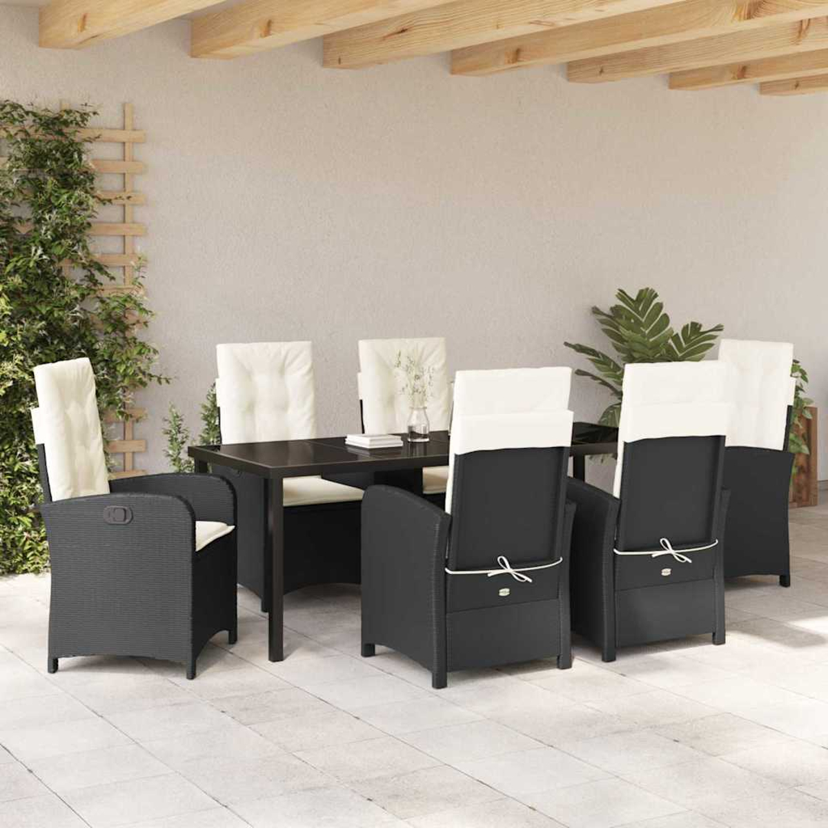 Essgruppe im Freien: schwarze Stühle mit weißen Kissen um einen dunklen Tisch. Grüne Pflanzen und Holzbalken oben.