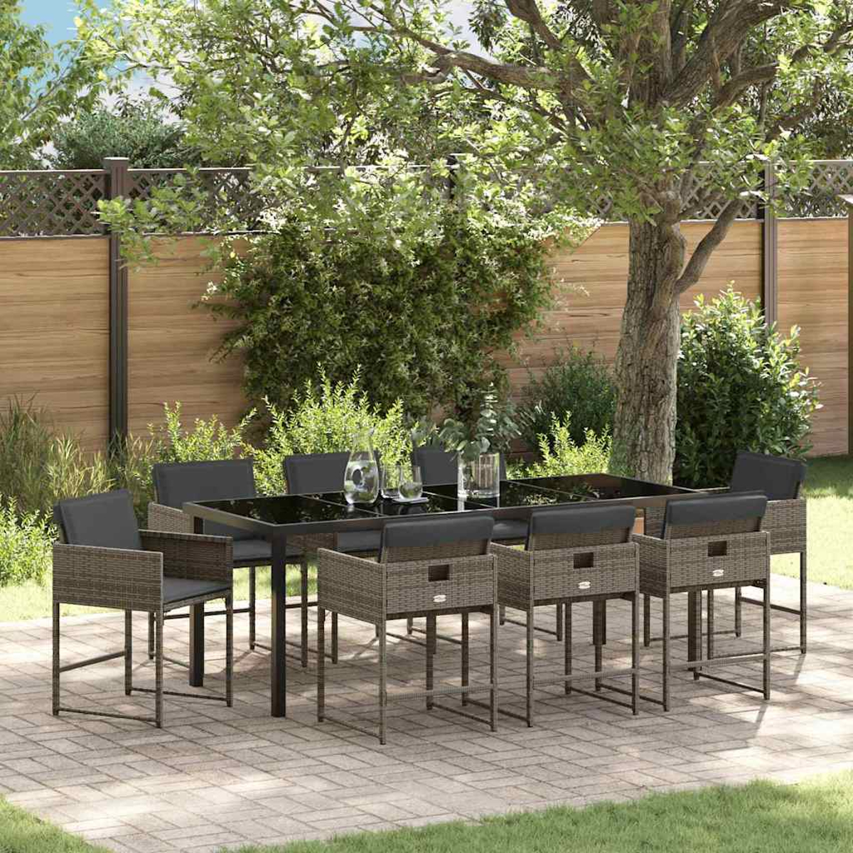 Essgruppe im Freien mit schwarzem Tisch, Stühlen und Gartenhintergrund mit Bäumen und Holzzaun.