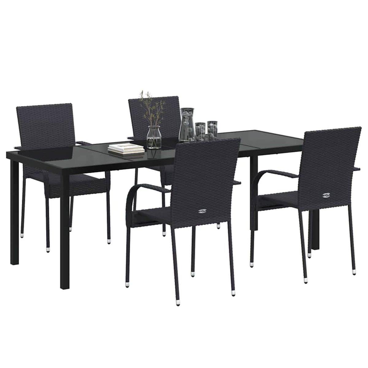 Ein schwarzer Tisch mit Glasplatte und vier dunkelgrauen Stühlen. Auf dem Tisch stehen Gläser, eine Vase mit Zweigen und Bücher.