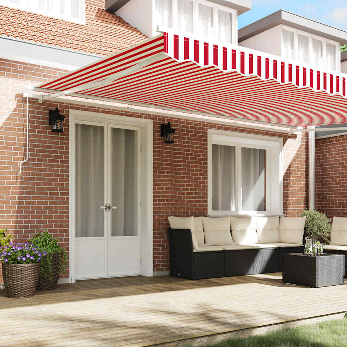 Un toldo a rayas rojas y blancas cubre un patio. Una pared de ladrillo tiene una puerta, ventana y juego de sofás. Se ven plantas en macetas.