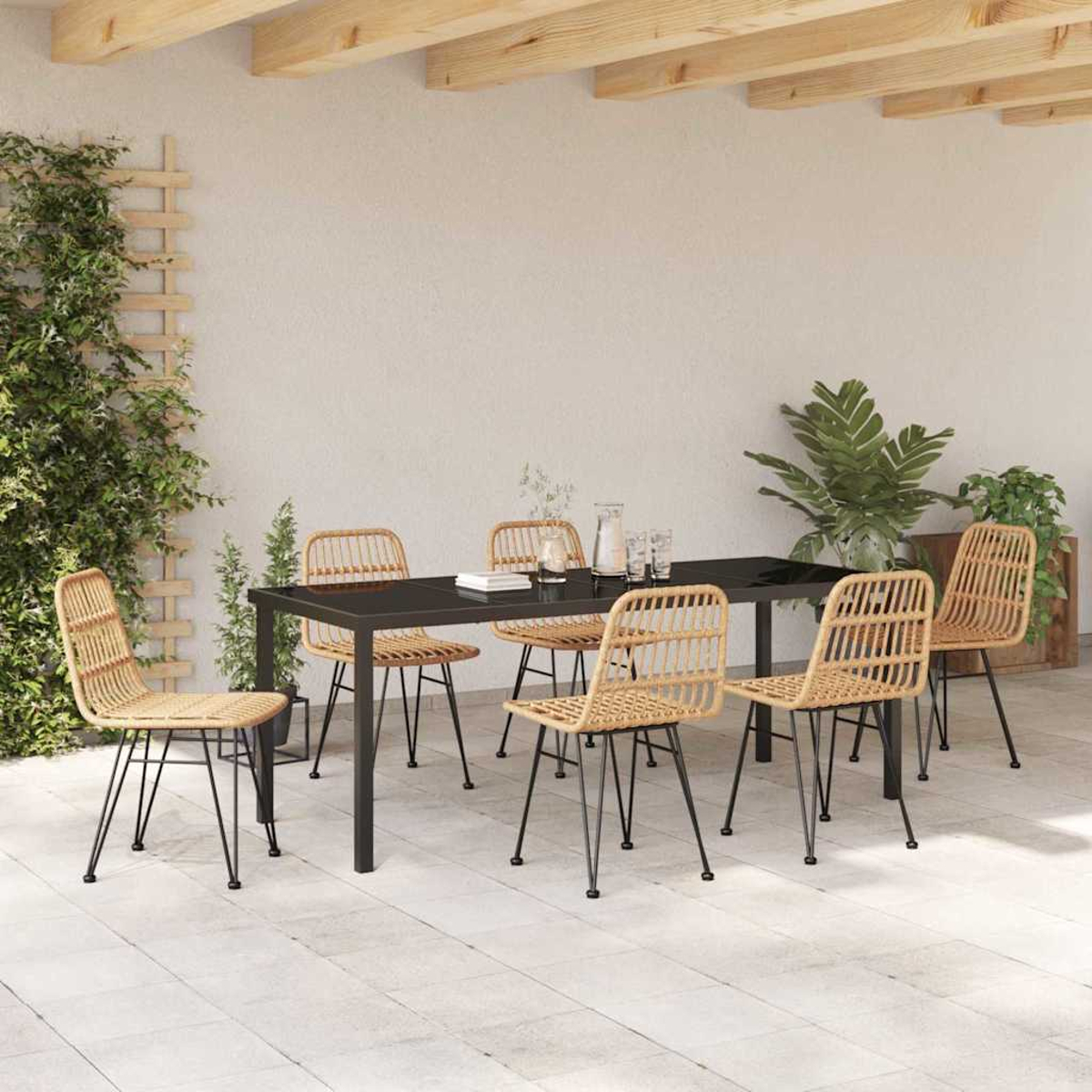 Set da pranzo all'aperto con tavolo nero, sei sedie in vimini, piante e parete bianca sotto una struttura in legno.