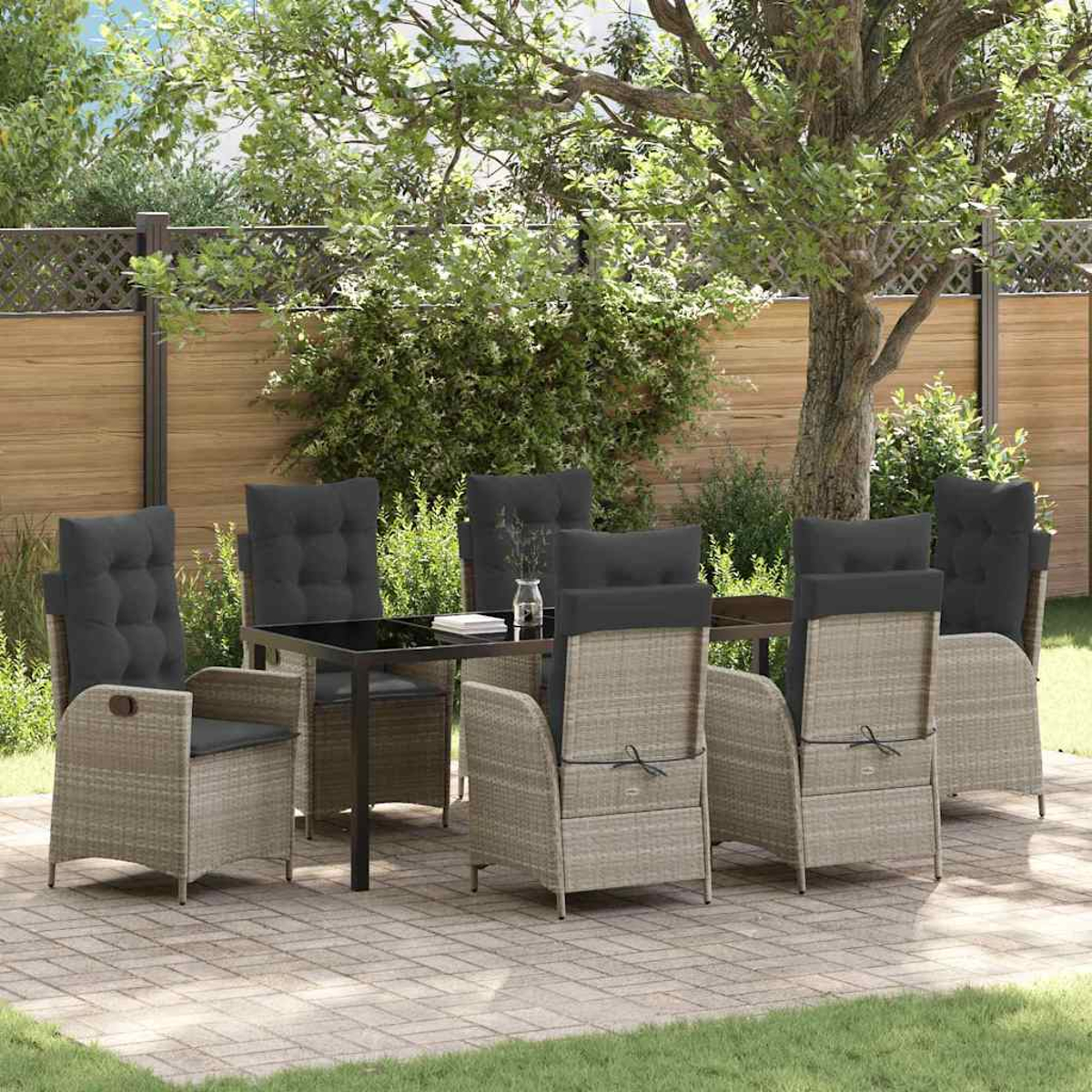 Essgruppe im Freien. Rattan-Stühle mit grauen Kissen umgeben einen schwarzen Tisch. Die Szene spielt auf einer Terrasse mit Bäumen und einem Zaun.