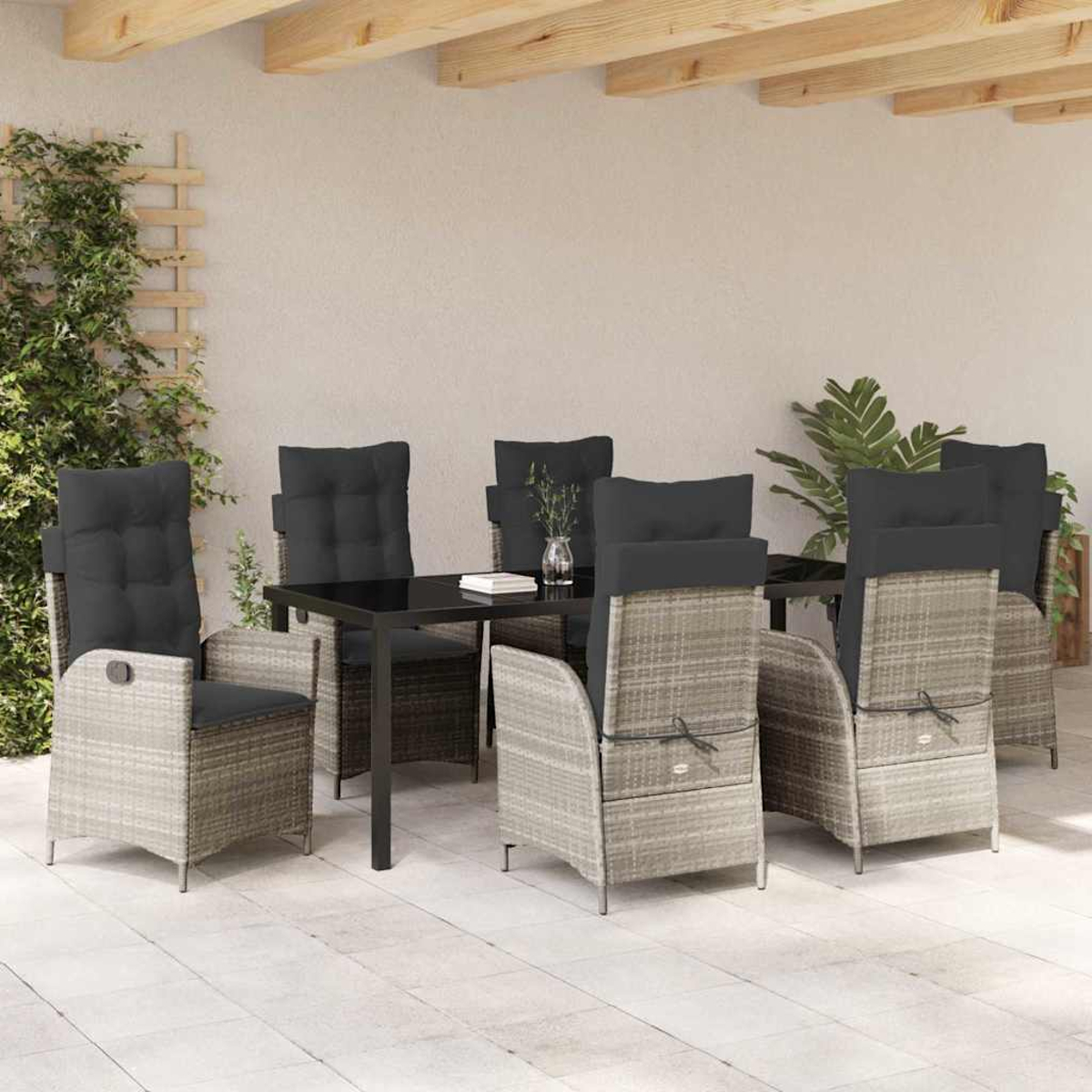 Essgruppe im Freien mit sechs grauen Korbstühlen und einem schwarzen Tisch auf einer Terrasse. Grünpflanzen an der Seite.