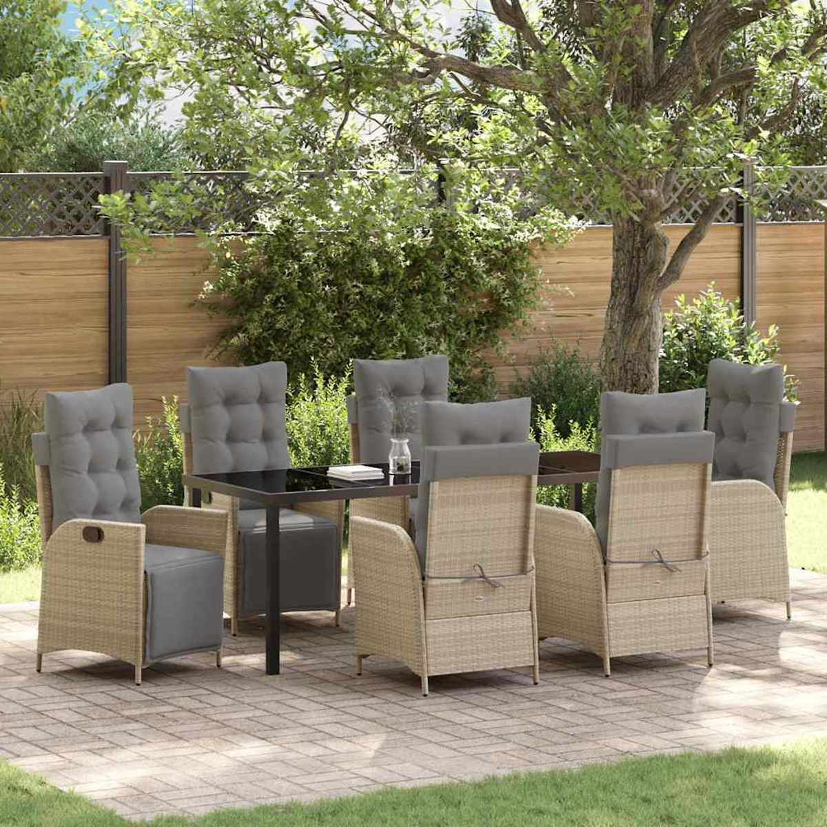 Essgruppe im Freien. Rattan-Stühle mit grauen Kissen umgeben einen schwarzen Tisch. Die Szene spielt sich auf einer Terrasse mit Holzzaun und Grün ab.