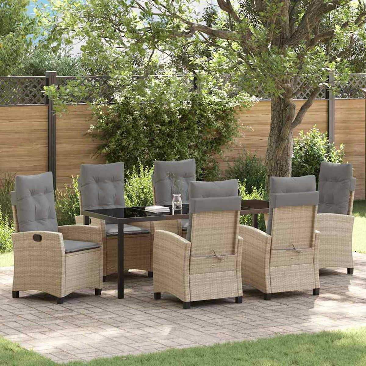 Ein Terrassenset mit sechs Korbstühlen und grauen Kissen um einen schwarzen Tisch. Die Szene ist im Freien mit einem Baum und Holzzaun.