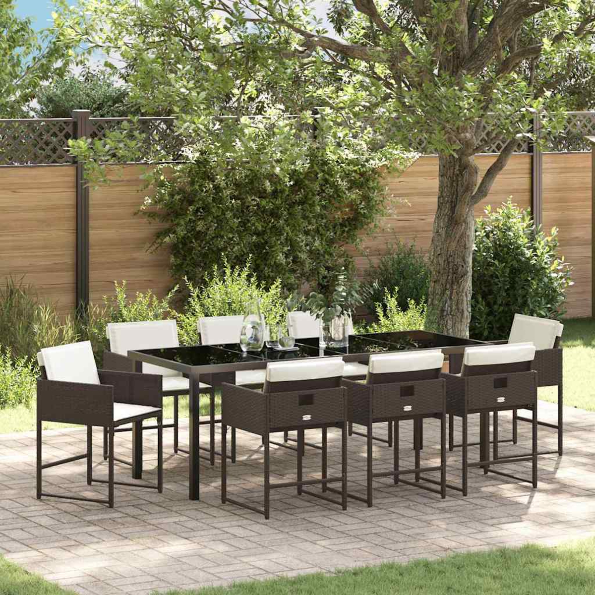 Essgruppe im Freien mit einem schwarzen Tisch und braunen Stühlen, auf einer Terrasse mit Holzzaun und Grün im Hintergrund.