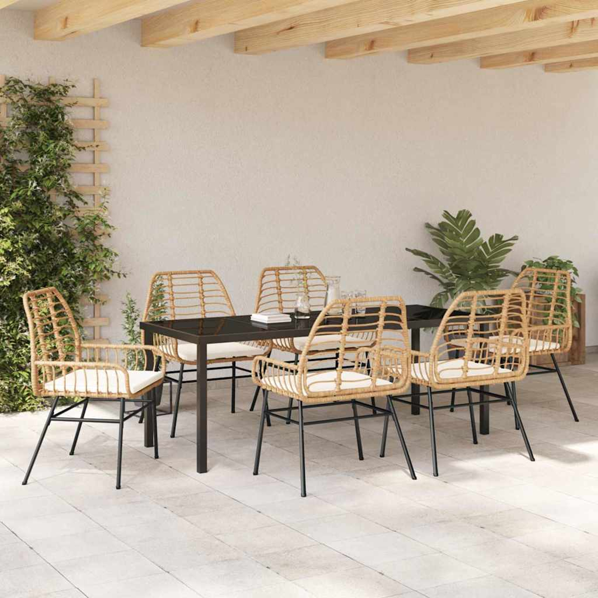 Terrassengarnitur im Freien: schwarzer Tisch, sechs Korbstühle mit weißen Kissen und Pflanzen. Helle Holzbalken, weißer Wandhintergrund.