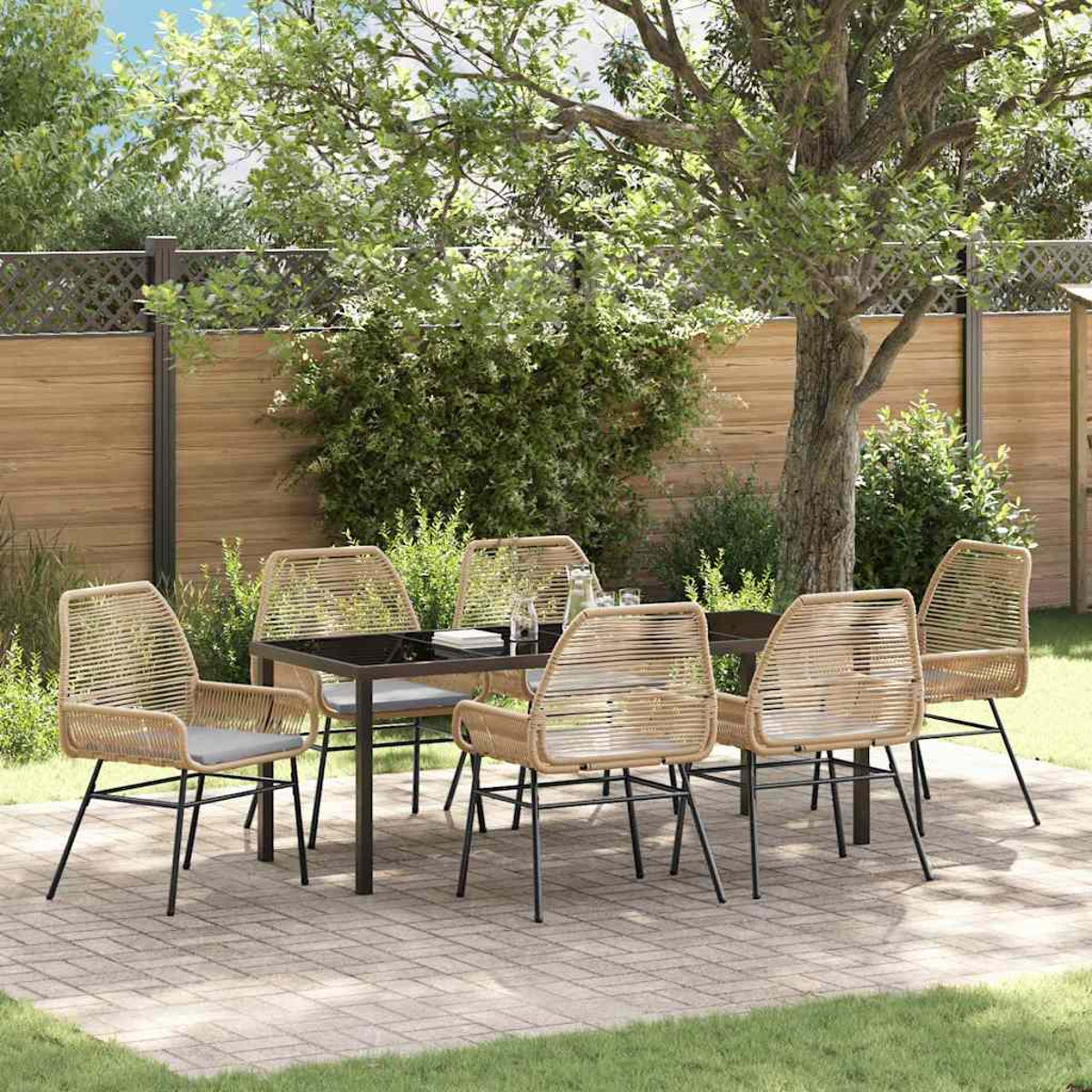 Essgruppe im Freien mit gewebten Stühlen und schwarzem Tisch auf einer Terrasse, mit Bäumen und Holzzaun im Hintergrund.