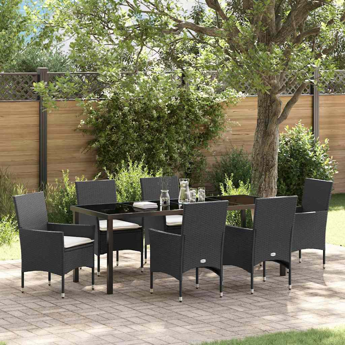 Juego de comedor al aire libre: una mesa negra con ocho sillas, sobre un patio de ladrillos. Un árbol y una valla de madera al fondo.