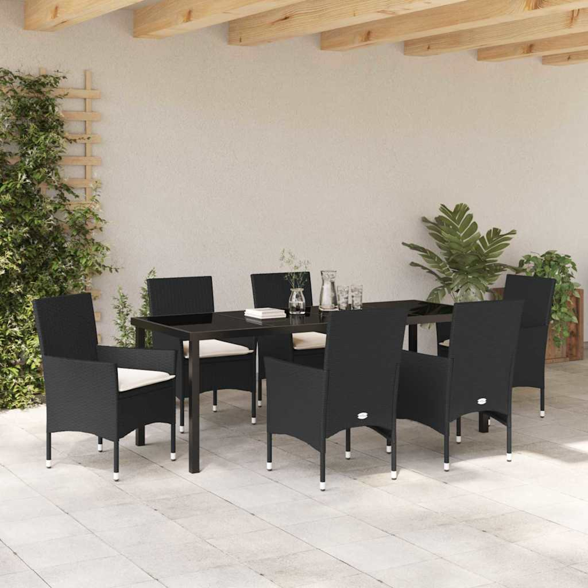 Juego de comedor al aire libre con sillas y mesa negras. Plantas en el fondo. Vigas de madera arriba. Patio pavimentado.