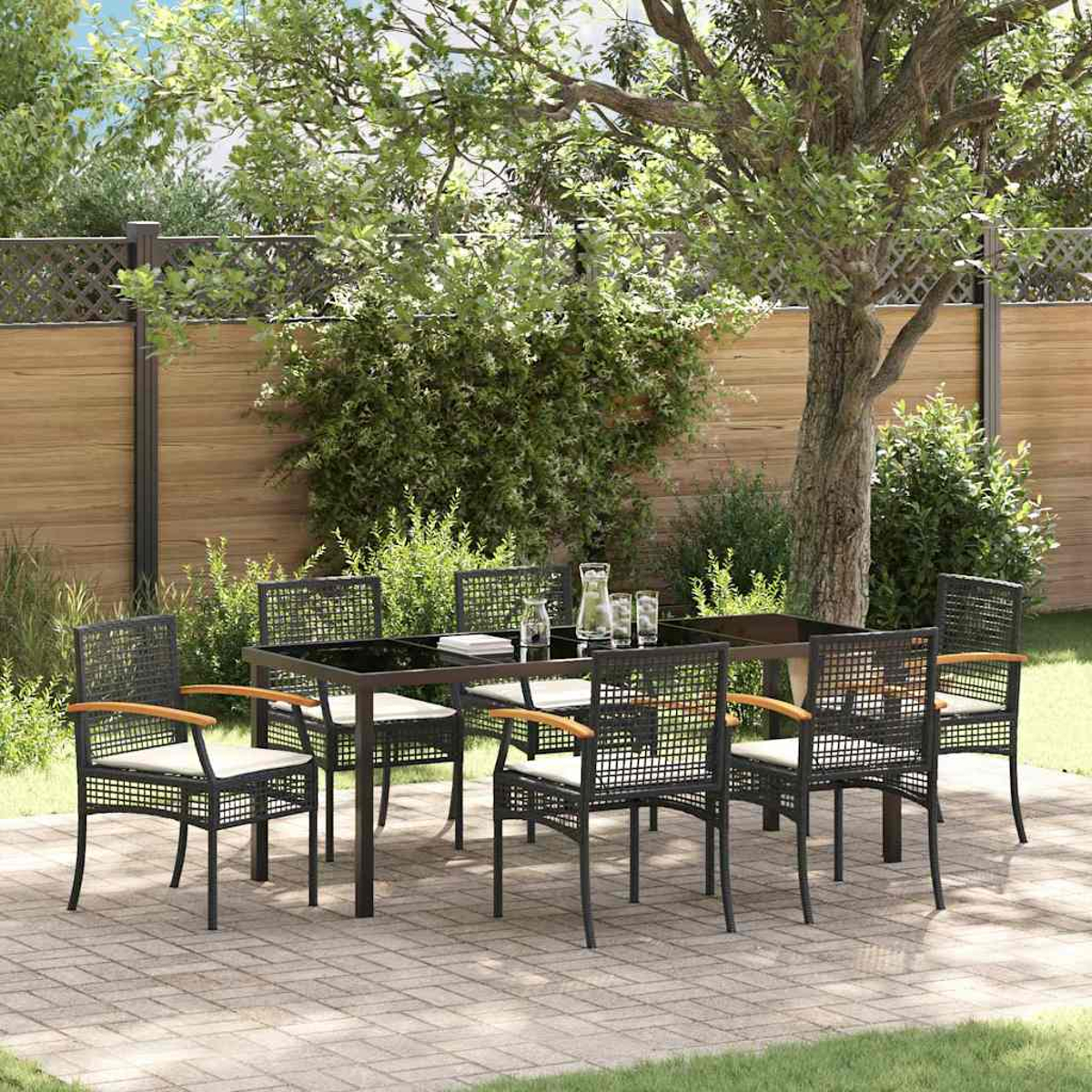 Set da pranzo all'aperto con tavolo e sedie neri. L'ambiente comprende un albero, arbusti, una recinzione in legno e un patio in mattoni.