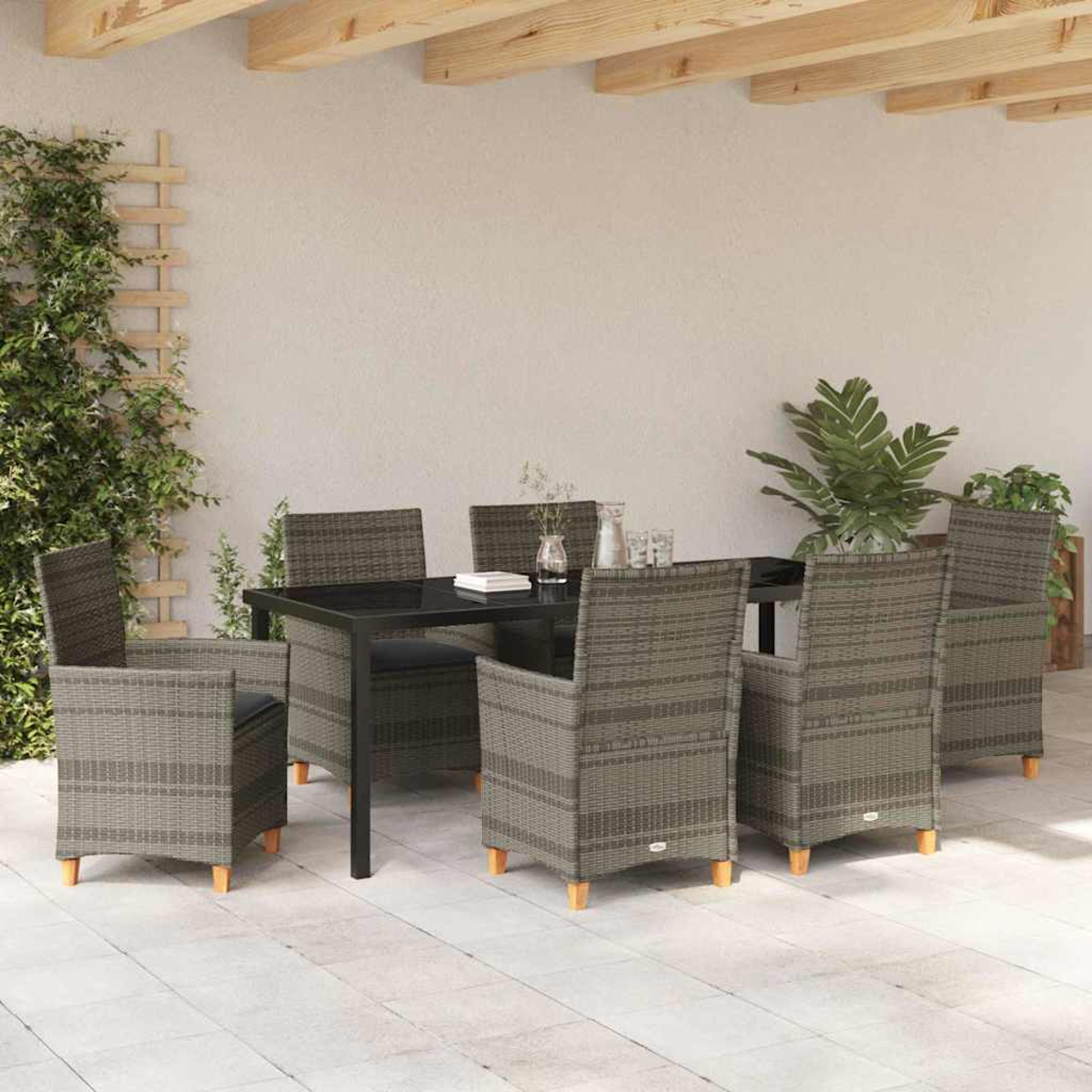 Essgruppe im Freien mit schwarzem Tisch und sechs grauen Korbstühlen. Grüne Pflanzen und ein Spalier sind sichtbar. Die Umgebung ist eine Terrasse.