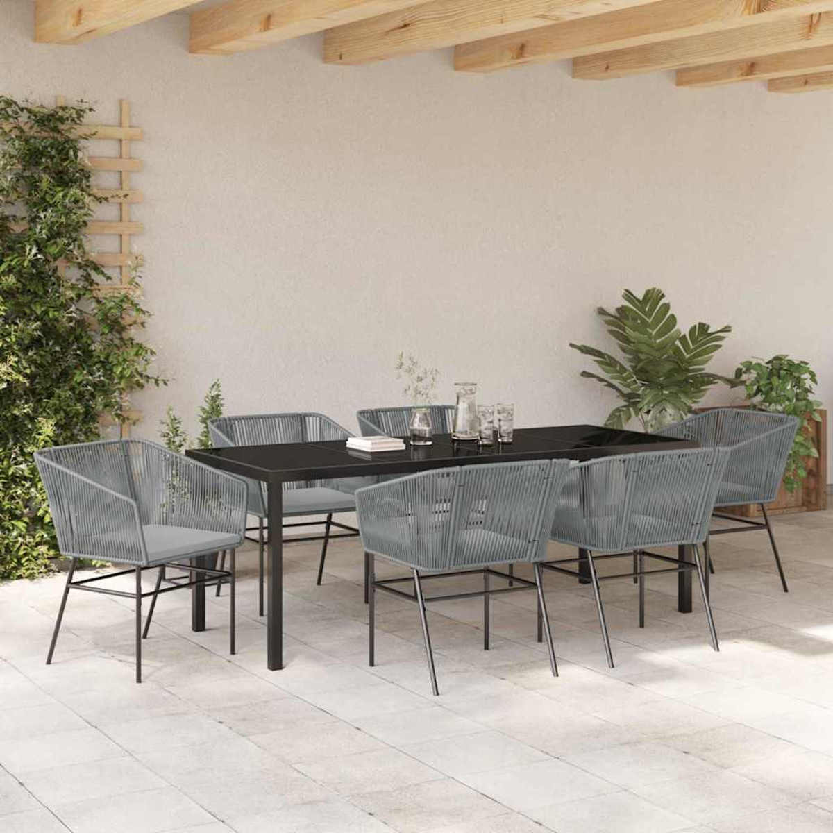 Essgruppe im Freien: schwarzer Tisch, sechs graue Stühle, Pflanzen und Holzbalken. Fliesenboden und neutrale Wand.