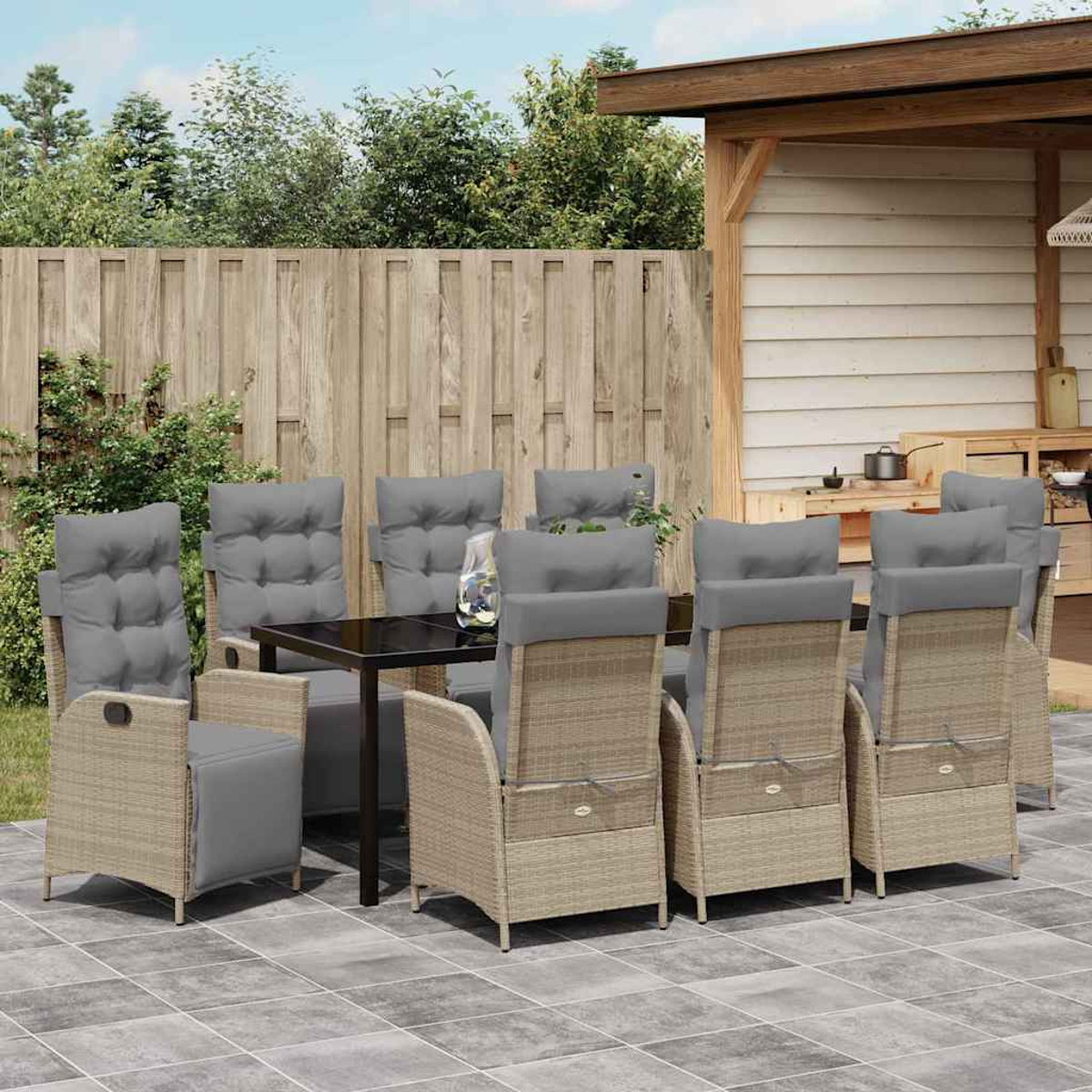 Essgruppe im Freien mit Tisch und Stühlen. Die Stühle haben graue Kissen, und die Umgebung befindet sich auf einer Terrasse.