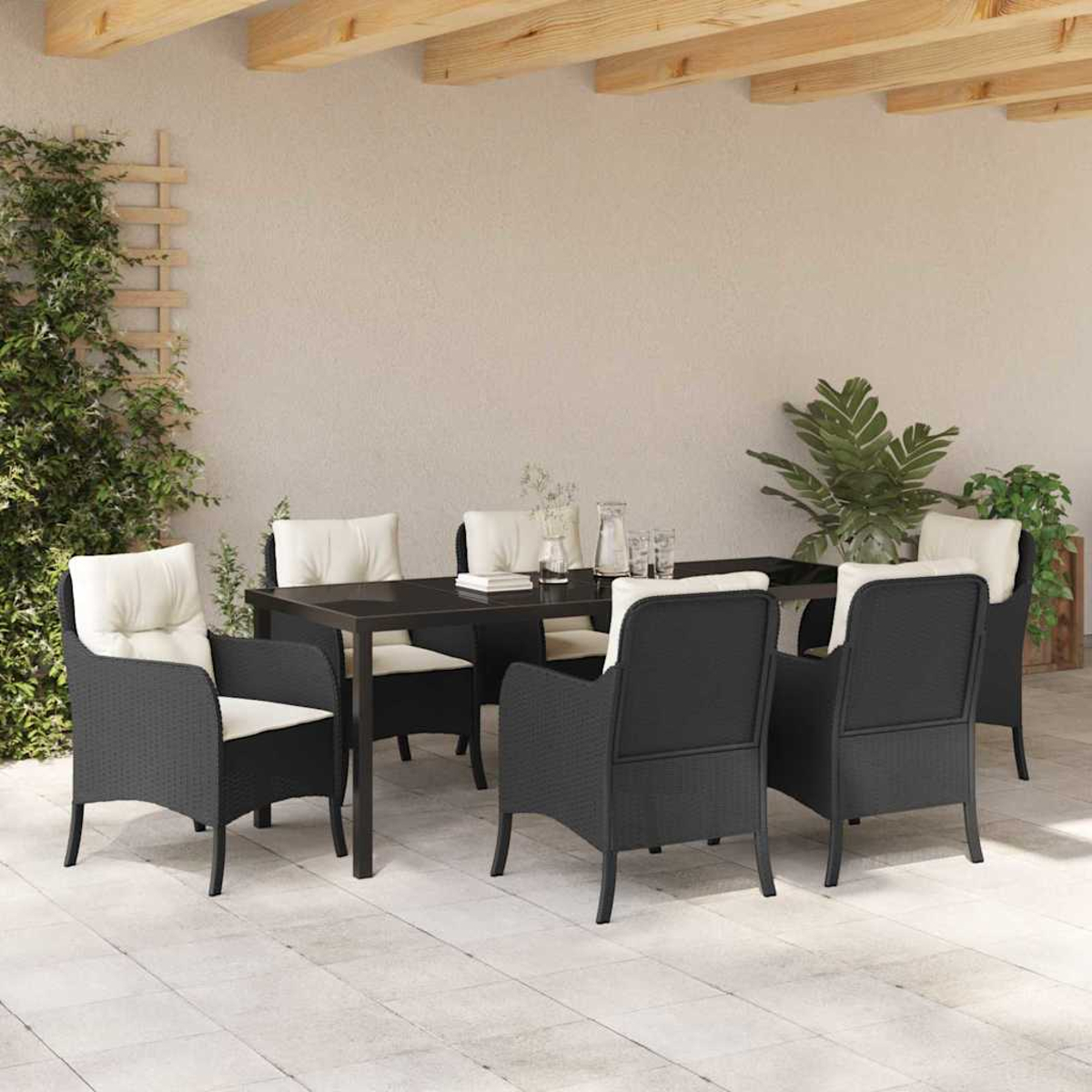 Essgruppe im Freien mit schwarzen Stühlen und weißen Kissen um einen schwarzen Tisch. Pflanzen und Holzbalken im Hintergrund.