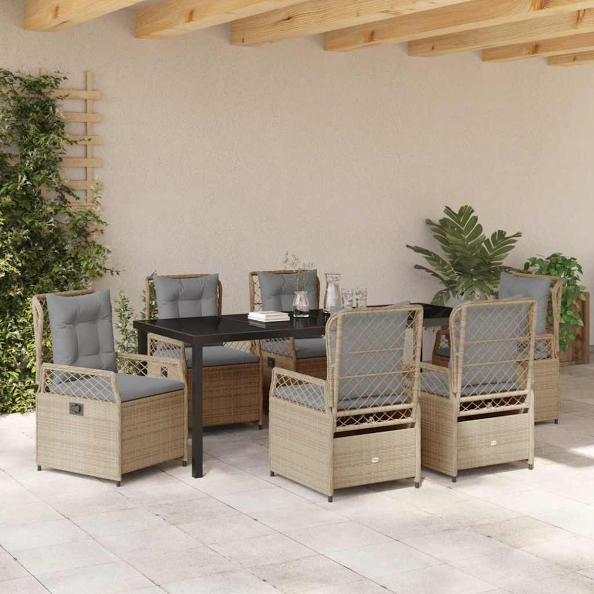 Terrassengarnitur: Tisch mit Stühlen, graue Kissen, beiges Geflecht. Pflanzen und ein Spalier befinden sich links.