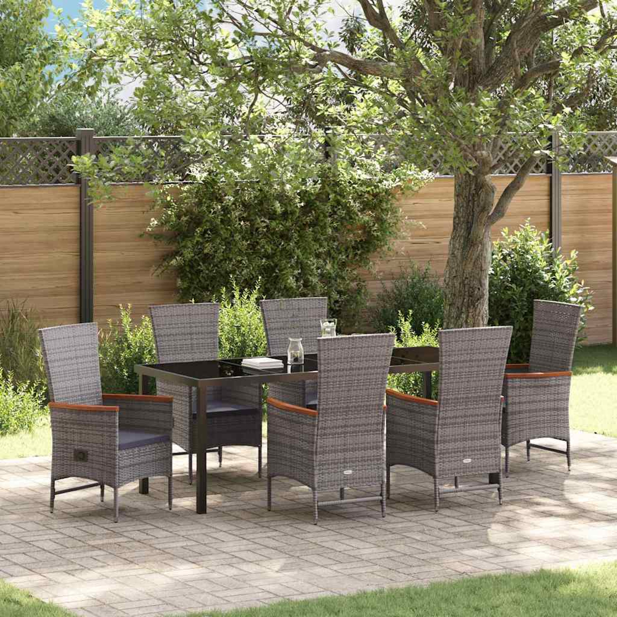 Ein Terrassenset mit sechs grauen Korbstühlen und einem schwarzen Tisch. Der Hintergrund zeigt Bäume, einen Zaun und eine Ziegelpatio.