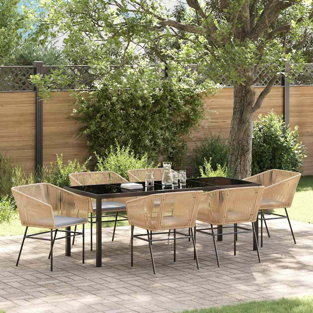 Essgruppe im Freien. Schwarzer Tisch mit sechs Stühlen. Ziegel-Terrasse. Bäume und Holzzaun im Hintergrund.
