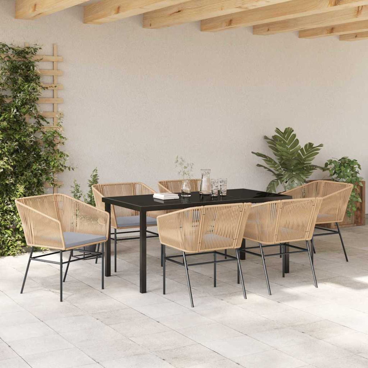 Essgruppe im Freien mit schwarzem Tisch und Korbstühlen. Pflanzen und ein Spalier sind links zu sehen.