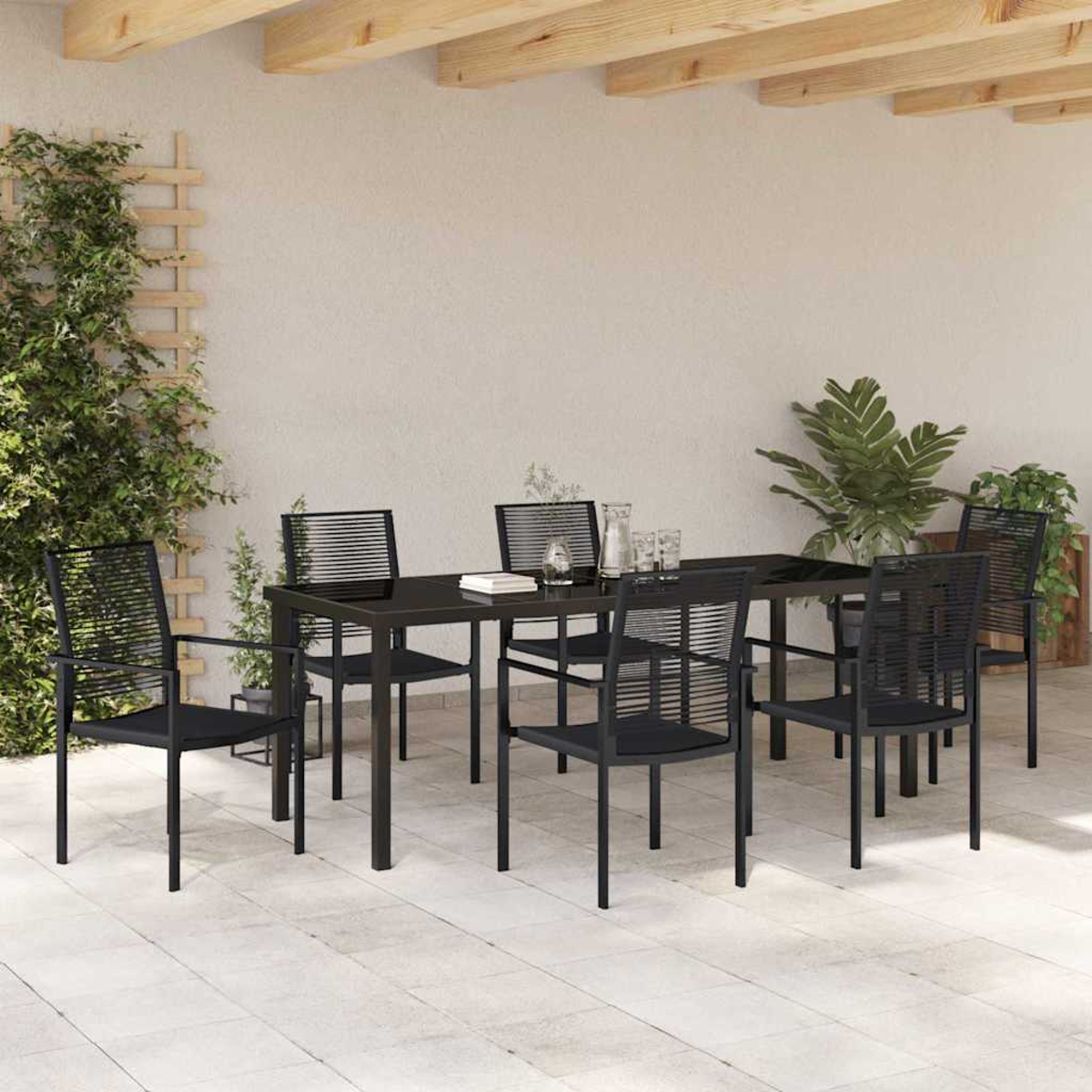 Essgruppe im Freien mit schwarzem Tisch und Stühlen. Pflanzen und ein Spalier sind sichtbar. Die Umgebung befindet sich unter einer Holzbalkenkonstruktion.