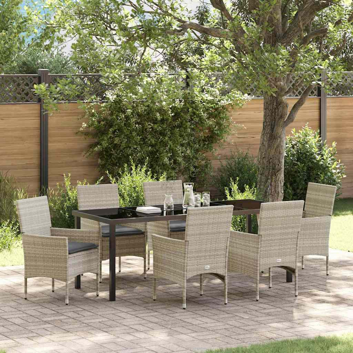 Eine Szene auf der Terrasse zeigt einen Tisch mit Stühlen. Im Hintergrund sind ein Baum und ein Zaun zu sehen. Gläser und eine Wasserkaraffe stehen auf dem Tisch.