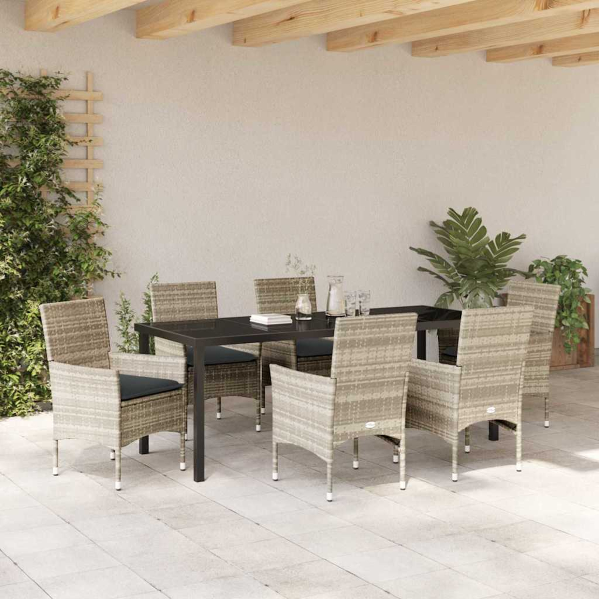 Essgruppe im Freien mit sechs Stühlen, einem schwarzen Tisch und Pflanzen vor einer weißen Wand unter einer Holzkonstruktion.