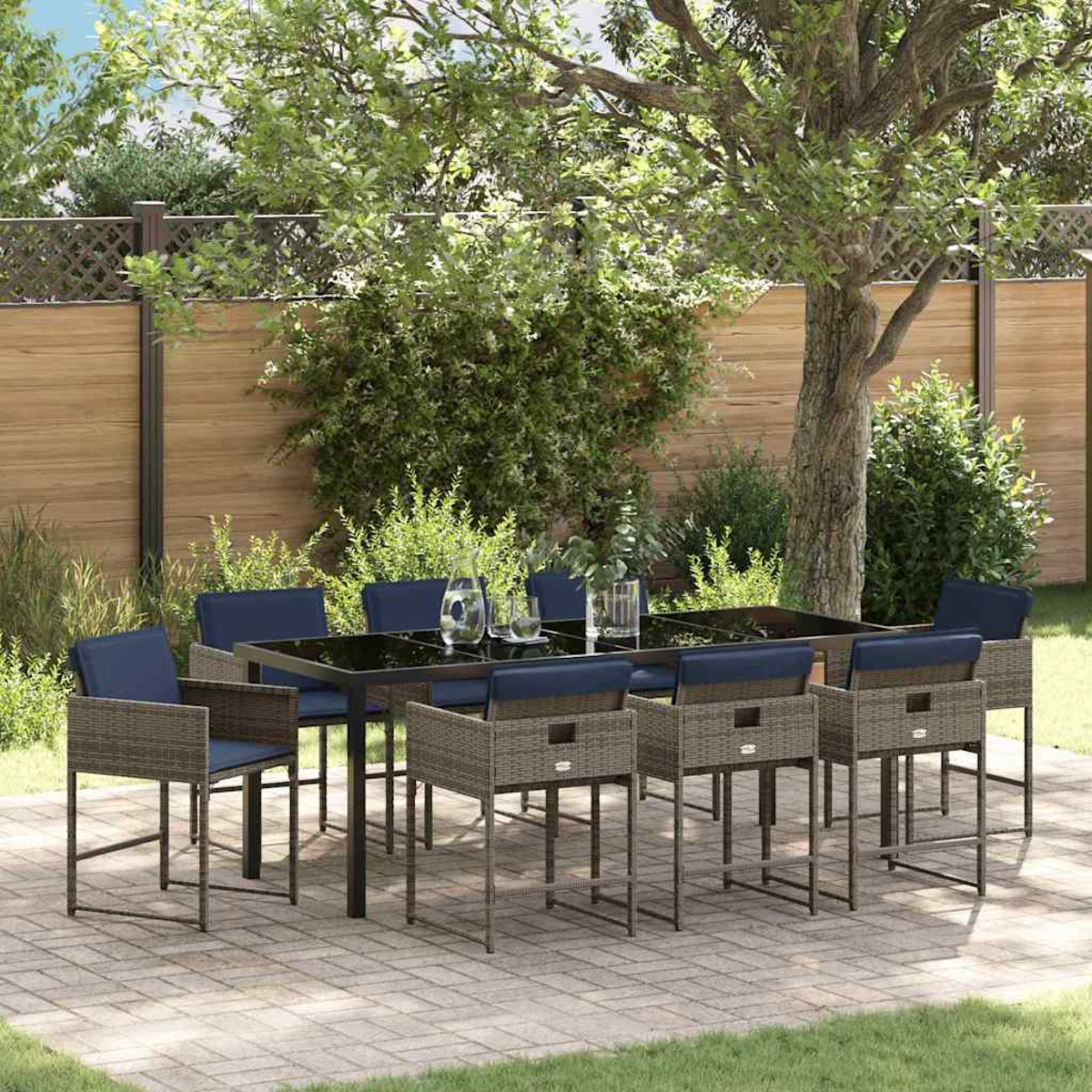 Essgruppe im Freien mit schwarzem Tisch und blauen Stühlen auf einer Terrasse. Grüne Bäume und ein Holzzaun im Hintergrund.