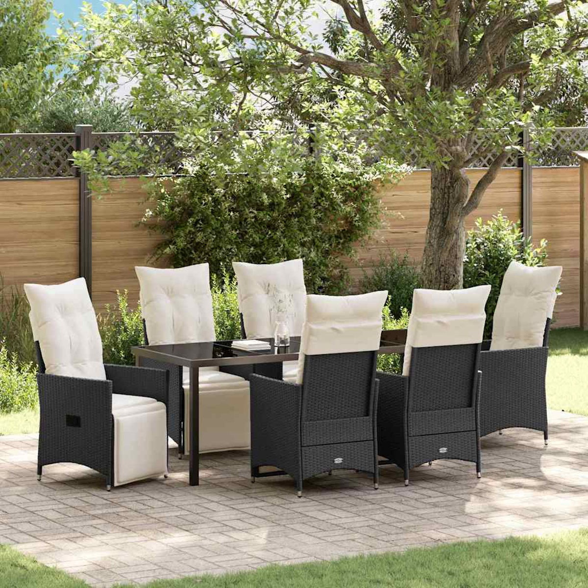 Eine Terrasse mit einem schwarzen Tisch und Stühlen mit cremefarbenen Kissen. Ein Holzzaun und grünes Gras sind im Hintergrund.
