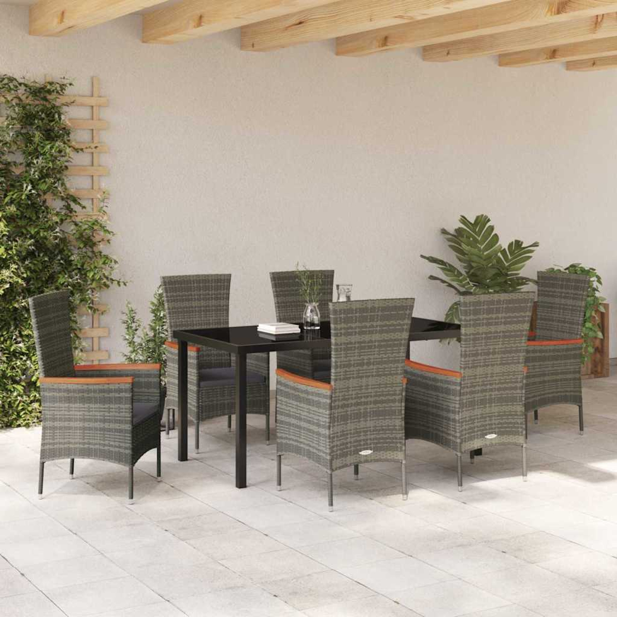 Terrassengarnitur im Freien mit schwarzem Tisch und sechs Stühlen. Pflanzen und ein Spalier befinden sich an der Seite, darüber Holzbalken.