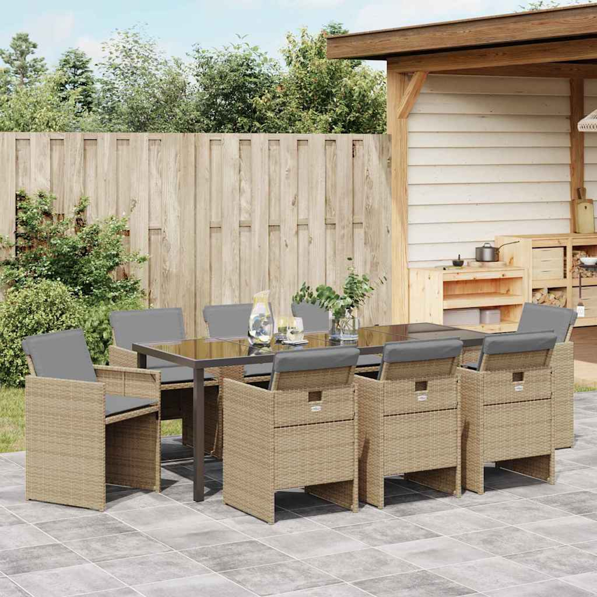 Outdoor-Essgruppe mit Glastisch und sechs geflochtenen Stühlen mit grauen Kissen auf einer gefliesten Terrasse.