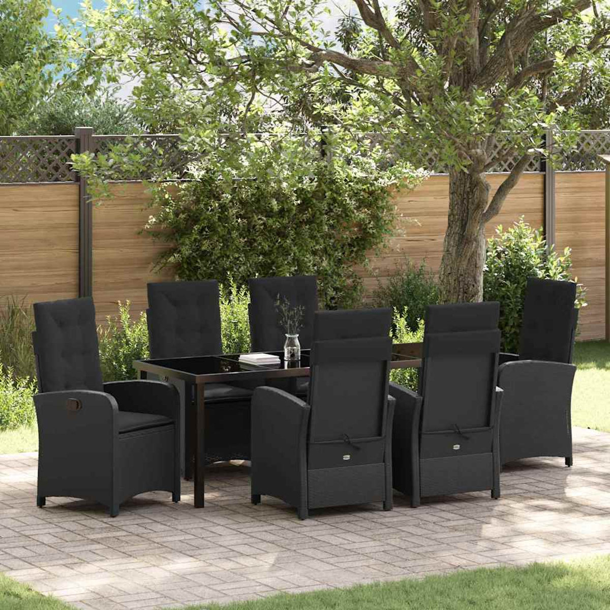 Essgruppe im Freien. Schwarze Stühle und Tisch auf einer Terrasse. Grüne Bäume und ein Holzzaun im Hintergrund.