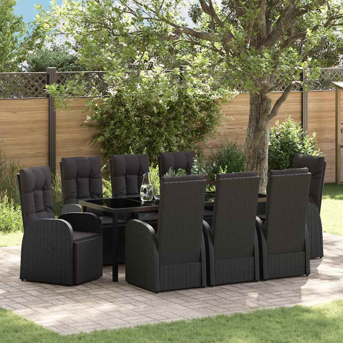 Ein schwarzes Ess-Set im Freien auf einer Terrasse, mit Tisch und Stühlen, vor dem Hintergrund von Bäumen und einem Holzzaun.