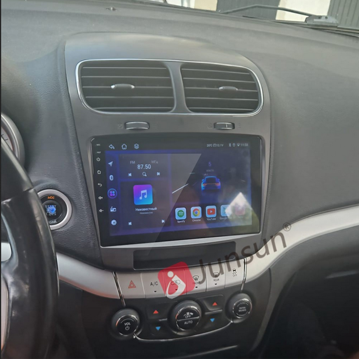 Deska rozdzielcza samochodu z ekranem dotykowym wyświetlającym muzykę i aplikacje. Otwory wentylacyjne u góry, elementy sterujące na dole. Kierownica po lewej.