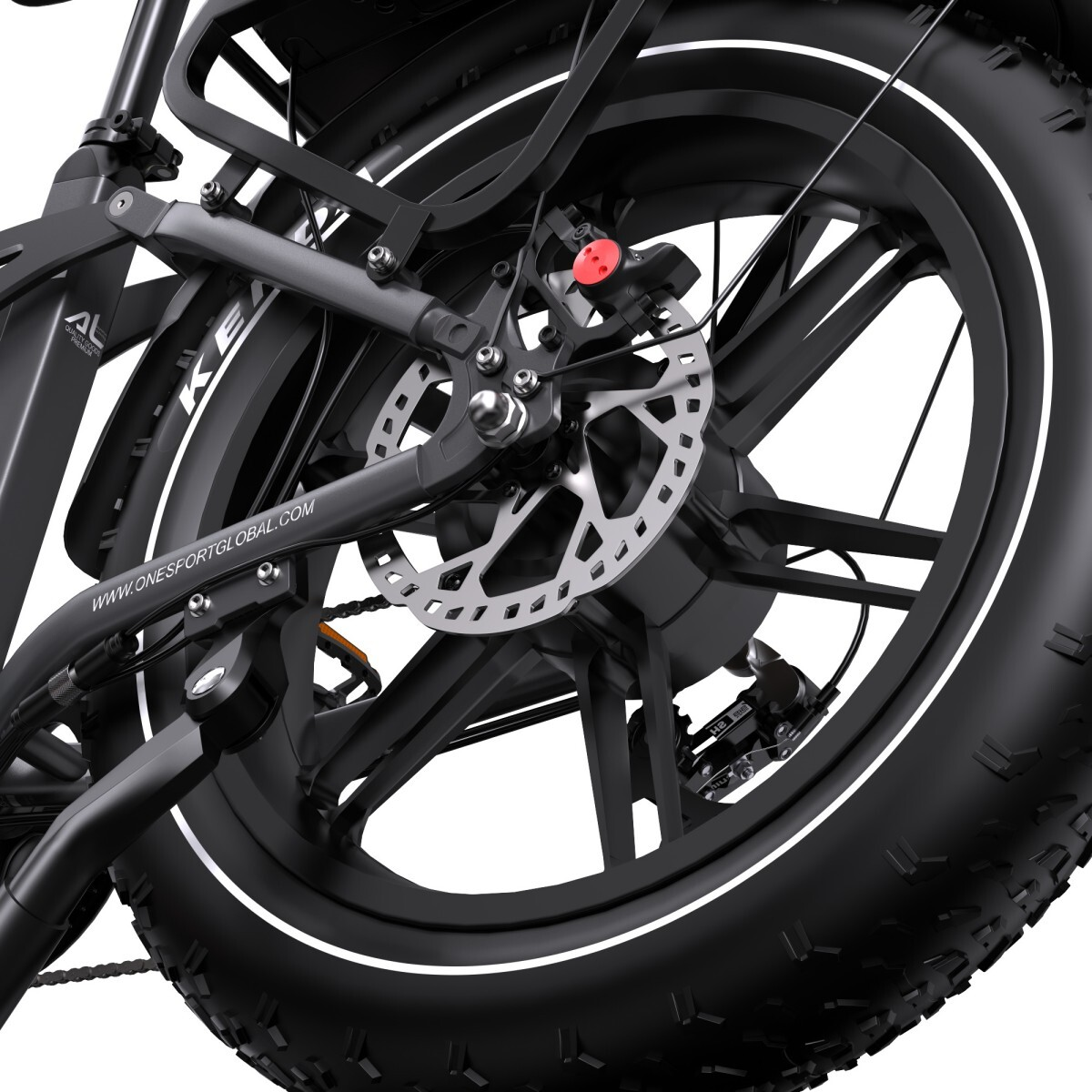 Zbliżenie czarnego koła rowerowego. Widoczny jest srebrny hamulec tarczowy. Opona ma biały pasek. Czerwony element znajduje się na hamulcu.