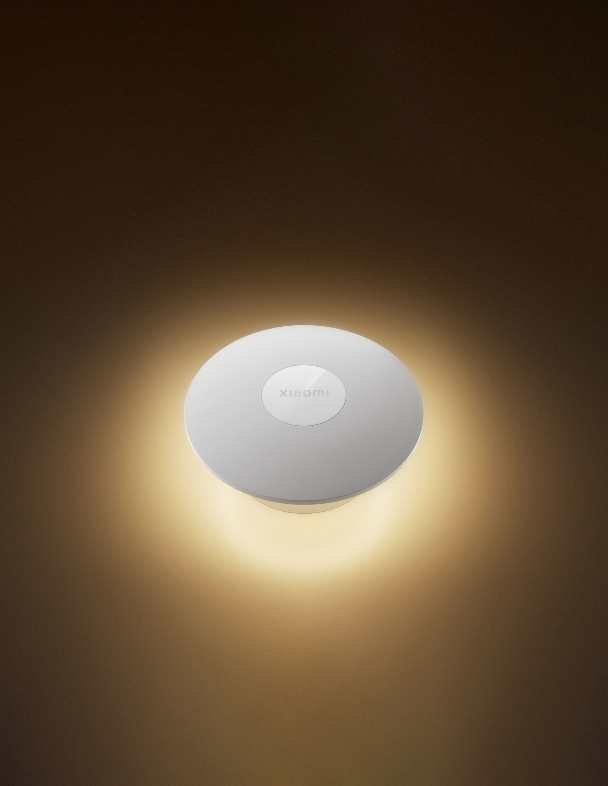 Eine weiße Xiaomi Deckenleuchte ist zentriert. Sie strahlt ein warmes Licht gegen eine braune Wand aus.