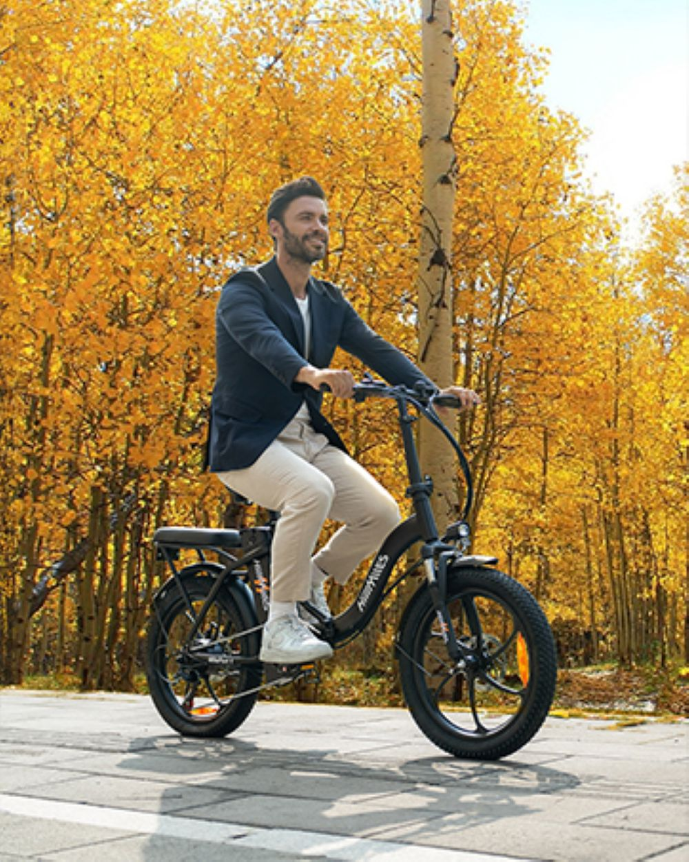 Un hombre monta en bicicleta eléctrica en una carretera pavimentada. El fondo está lleno de árboles amarillos de otoño.