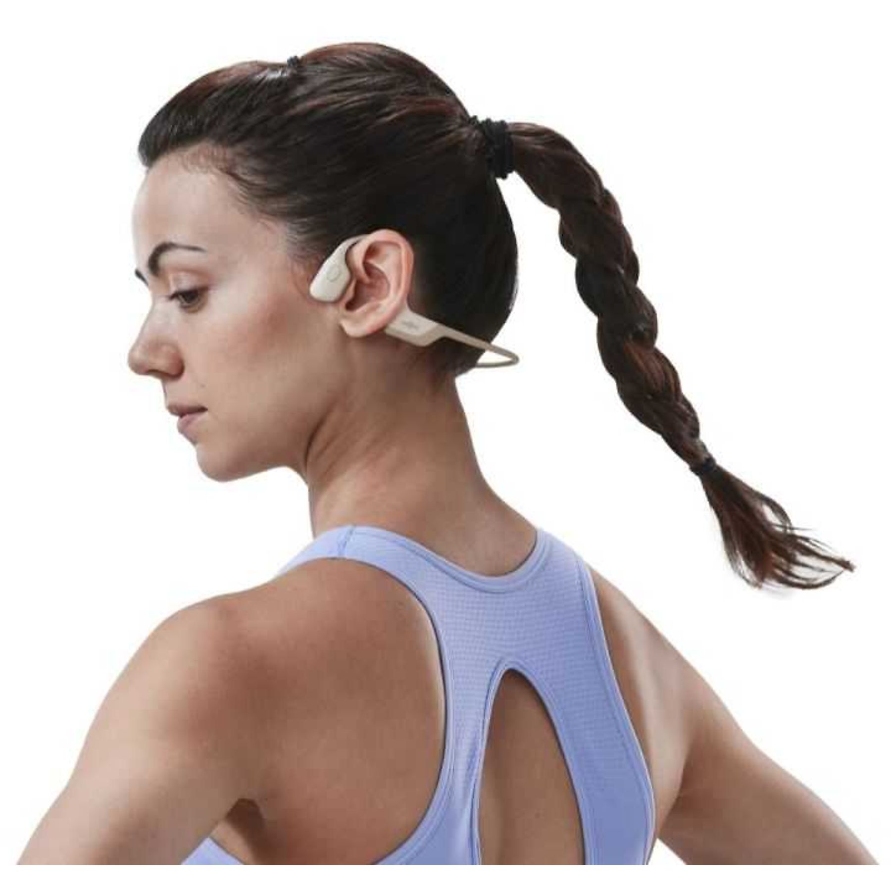 Donna con cuffie a conduzione ossea. Ha i capelli scuri in una treccia e indossa una canotta blu.