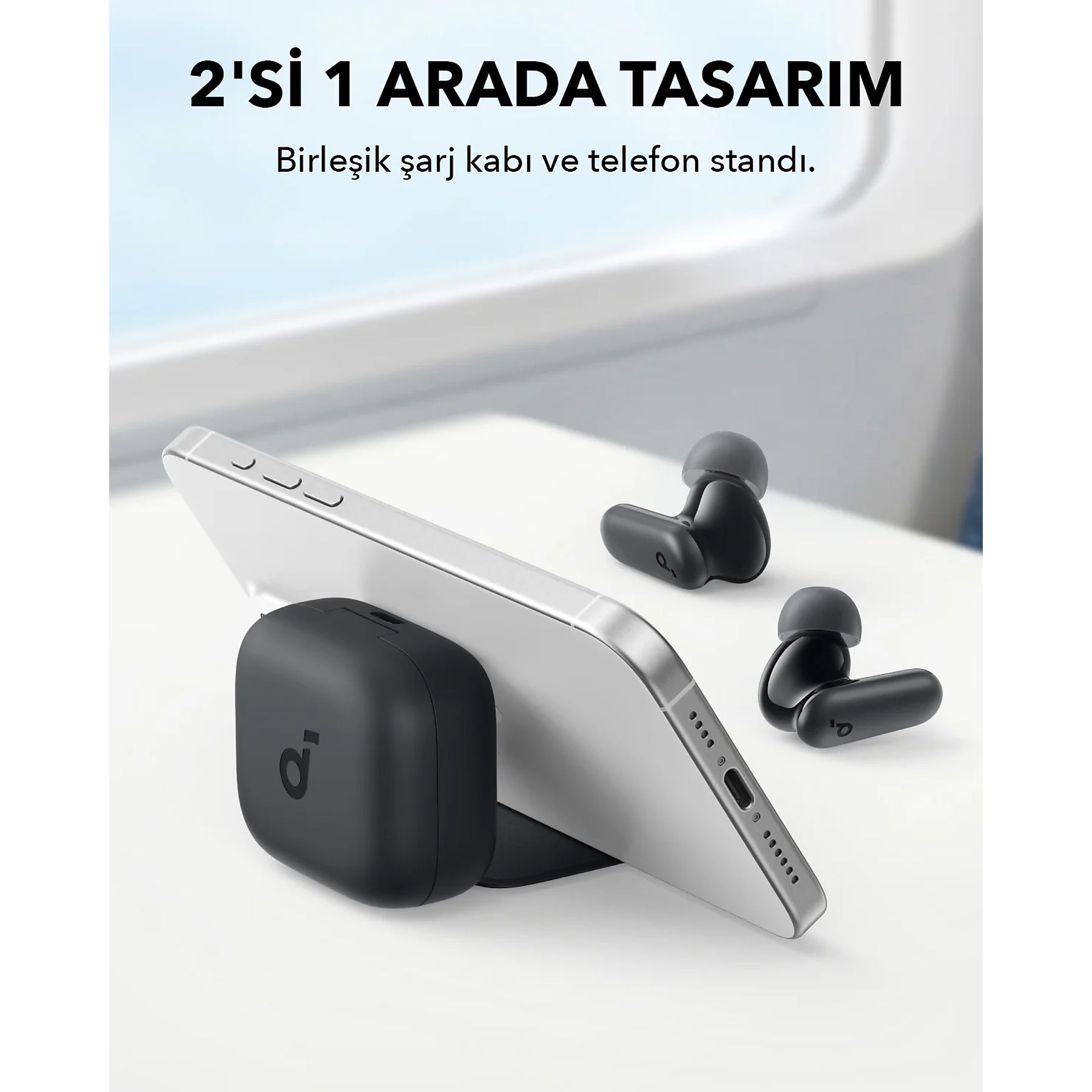 Telefono nero su un supporto di ricarica, con auricolari neri accanto. Sfondo bianco.