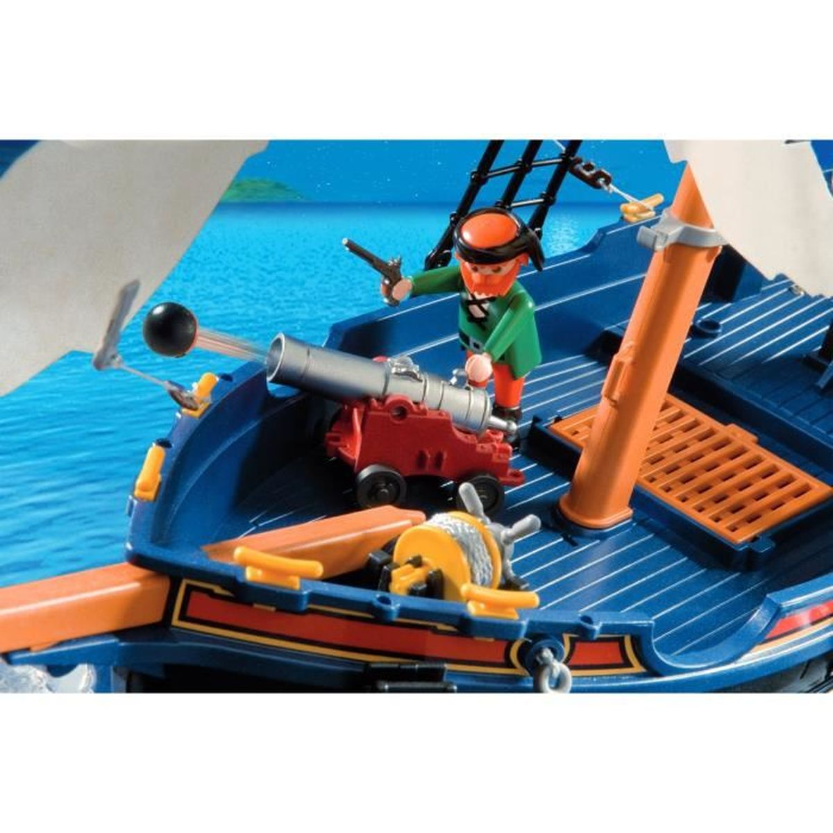 Una nave pirata giocattolo con un cannone che spara una palla di cannone, una figura di pirata e un timone. Mare blu sullo sfondo.