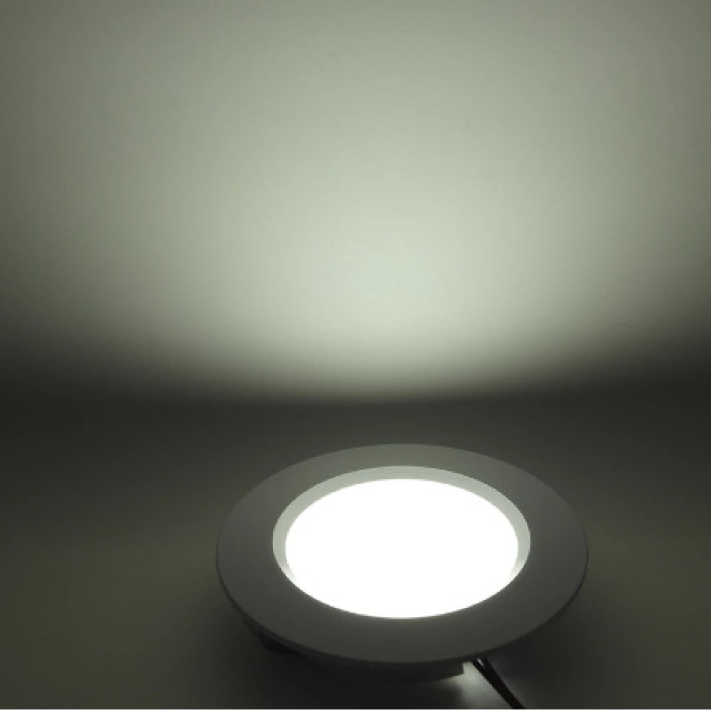 Eine runde, weiße Einbauleuchte ist beleuchtet. Das Licht ist hell, umgeben von einem weißen Rahmen, vor einem weißen Hintergrund.