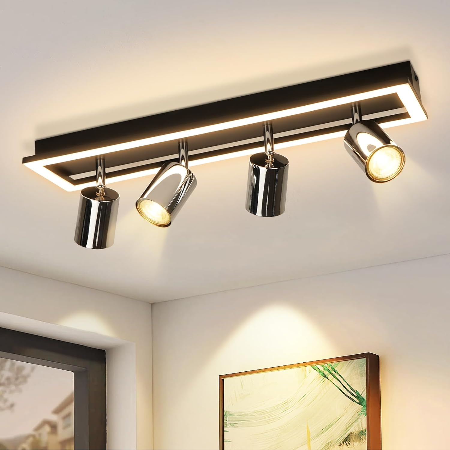 Un moderno apparecchio di illuminazione a soffitto con quattro faretti metallici. È montato su un telaio rettangolare nero con un bordo bianco brillante.